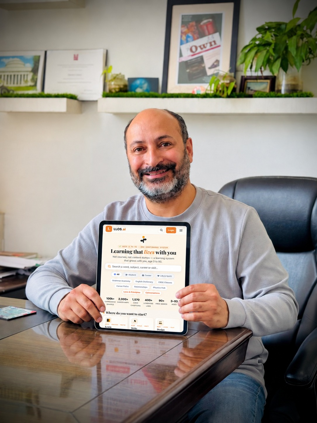 Pawan Nayar in his office, holding a tablet with the LLOS.ai home page open